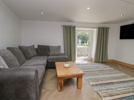A living room with a sofa coffee table and door at Old Post Office Cottage Ulverston