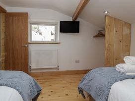 A bedroom with twin beds and a television at The Old Post Office Cottage in Ulverston