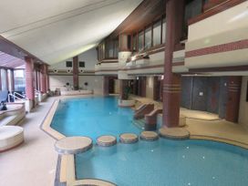 An indoor pool area with seating and plants at Old Post Office Cottage Backbarrow near Newby Bridge