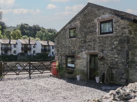 A stone building with a gate and planters at Old Post Office Cottage Backbarrow near Newby Bridge