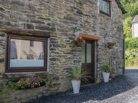An exterior view of a stone cottage with planters and hanging baskets at Old Post Office Cottage Backbarrow near Newby Bridge