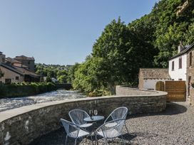 An outdoor area with a table and chairs near a river at Old Post Office Cottage Backbarrow near Newby Bridge
