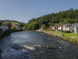 A scenery featuring a river beside houses at Old Post Office Cottage Backbarrow near Newby Bridge