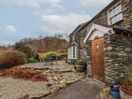 An outdoor seating area with a stone path and plants at Deer How Farm in Patterdale near Glenridding