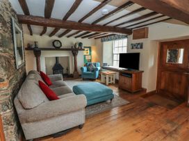A living room with a sofa, chair, coffee table, and television at Deer How Farm in Patterdale near Glenridding