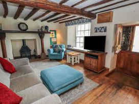 A living room with a fireplace, sofa, and television at Deer How Farm in Patterdale near Glenridding