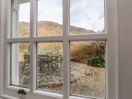 A view of a garden with a table and chairs through a window at Deer How Farm near Glenridding