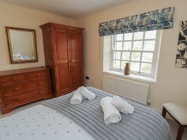 A bedroom with a wardrobe, chest of drawers, and window at Deer How Farm in Patterdale near Glenridding