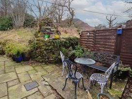 A garden with a table and chairs and a stone wall at Deer How Farm in Patterdale near Glenridding