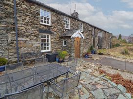 An outdoor area with a stone wall and seating at Deer How Farm Patterdale near Glenridding