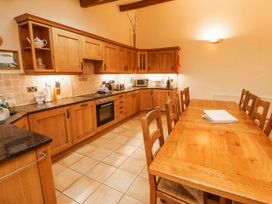 A kitchen with wooden cabinets and a dining table at Deer How Farm Patterdale near Glenridding