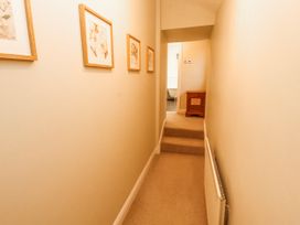 A hallway with artwork on walls and a staircase at Deer How Farm in Patterdale near Glenridding