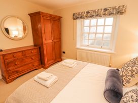 A bedroom with a bed, wardrobe, dresser and window at Deer How Farm in Patterdale near Glenridding