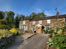 A stone house with a garden and driveway at Deer How Farm in Patterdale near Glenridding