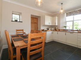 A kitchen and dining area with wooden table and chairs white cabinets and a large window at Glasfryn in Llandwrog