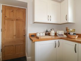 A kitchen corner with white cabinets wooden countertop kitchen appliances and a wooden door at Glasfryn in Llandwrog