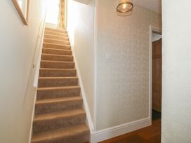 A carpeted staircase with a handrail and a light fixture in a hallway at Glasfryn in Llandwrog