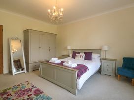 A bedroom with a bed set with pillows and towels a wardrobe a mirror and a blue chair at Glasfryn in Llandwrog