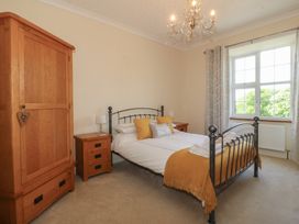A bedroom with a metal bed frame wooden wardrobes bedside tables and lamps at Glasfryn in Llandwrog