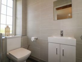 A bathroom with a toilet sink and mirror at Glasfryn in Llandwrog