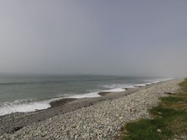 A beach with pebbles and grass by the ocean at Glasfryn in Llandwrog
