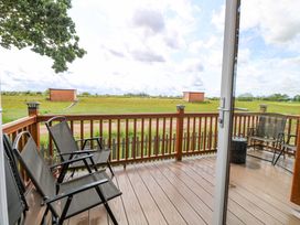 A deck with chairs and a view of the field at Oak Tree Holiday Lodge in Stonham Aspal