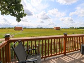 An outdoor view from a deck with a chair and grass at Oak Tree Holiday Lodge in Stonham Aspal