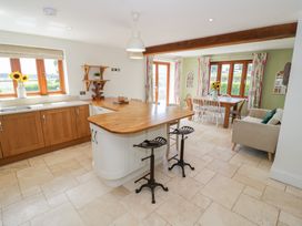 A kitchen with a counter, stools, and a dining table at Filly Brook in Bishop's Frome