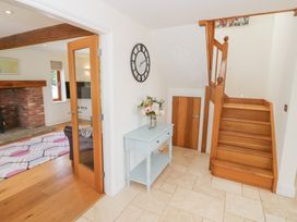 A hallway with a staircase and a flower arrangement at Filly Brook in Bishop's Frome