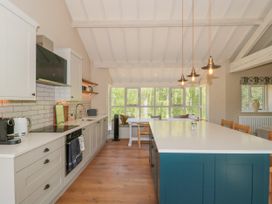 A kitchen with an island and stools at Cleveley Mill in Enstone