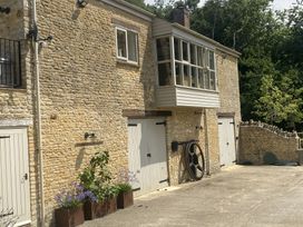 An outdoor view of a stone building with garage doors and planters at The Annexe, Cleveley Mill, Enstone