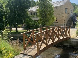 A wooden bridge over a stream near a building at The Annexe, Cleveley Mill in Enstone