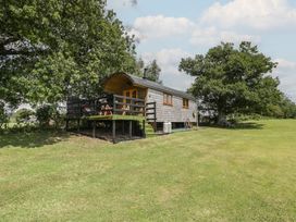 A hut with a deck surrounded by grass and trees at Shepherd Hut’s in Bristol