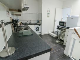 A kitchen with a stove, sink, and washing machine at Lady of the Lake Suite in Trearddur Bay