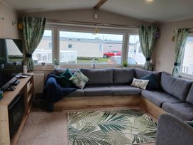 A living room with a sofa and television at Pines 15 in Porthcawl