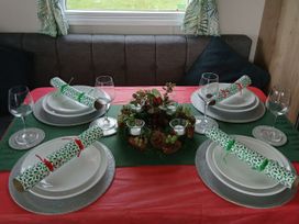 A dining table set with plates and glasses at Pines 15 in Porthcawl