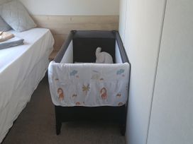 A crib and a bed in a bedroom at Pines 15 in Porthcawl