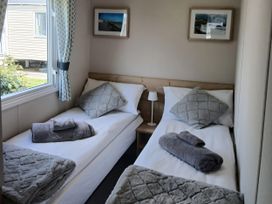 A bedroom with two beds and a window at Pines 15 in Porthcawl