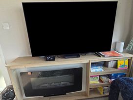 A living room with a television and entertainment unit at Pines 15 in Porthcawl