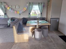 A living room with a sofa, table, and refrigerator at Pines 15 Porthcawl