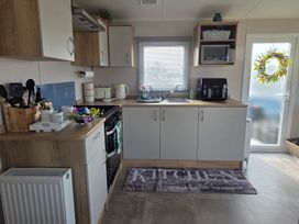 A kitchen with cabinets and appliances at Pines 15 in Porthcawl