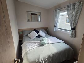 A bedroom with a double bed and a mirror at Pines 15 in Porthcawl