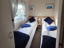 A bedroom with two single beds and a lamp at Pines 15 in Porthcawl