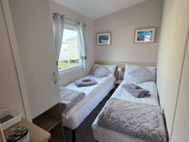 A bedroom with twin beds and a wardrobe at Pines 15 in Porthcawl