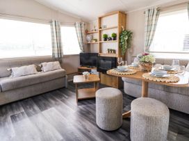 A living room with sofas a dining table with place settings a TV and shelves with plants at Lawi39 in Towyn