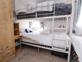 A bedroom with a bunk bed a wooden wardrobe and a rug at Lawi39 Towyn
