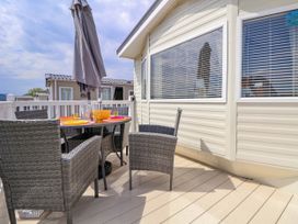 An outdoor patio with a table set for dining and four chairs at Lawi39 in Towyn