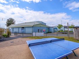 An outdoor area with a blue ping pong table in front of a light blue building with posters and string lights at Lawi39 in Towyn
