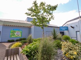 An exterior view of a building with a swimming pool sign and landscaped garden area with plants and a tree at Lawi39 in Towyn
