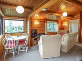 A living room with a sofa, table, and television at Y Bwthyn Pren, Cabin 209, Trawsfynydd